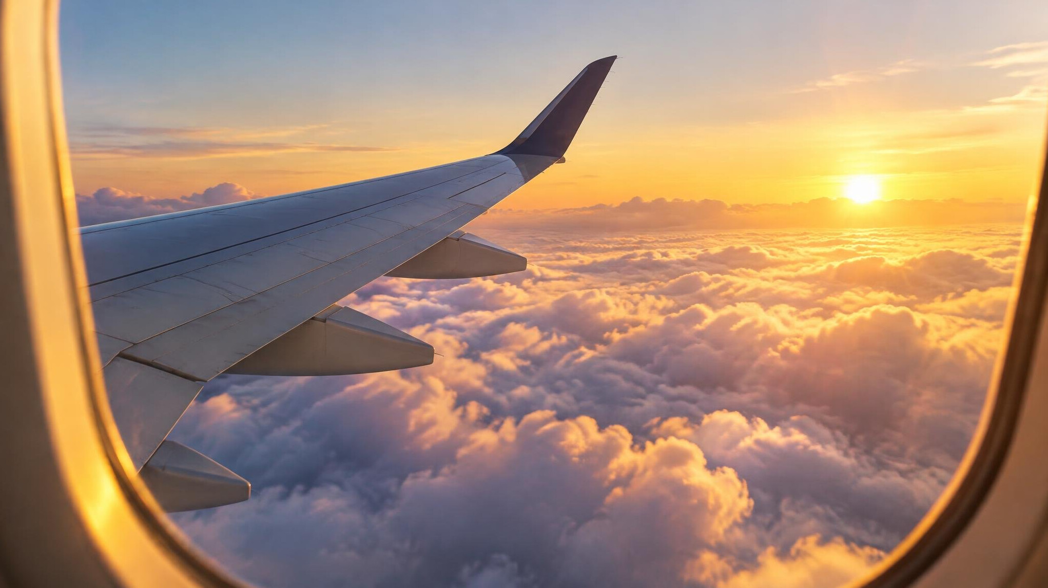 Airplane wing above the clouds at sunrise